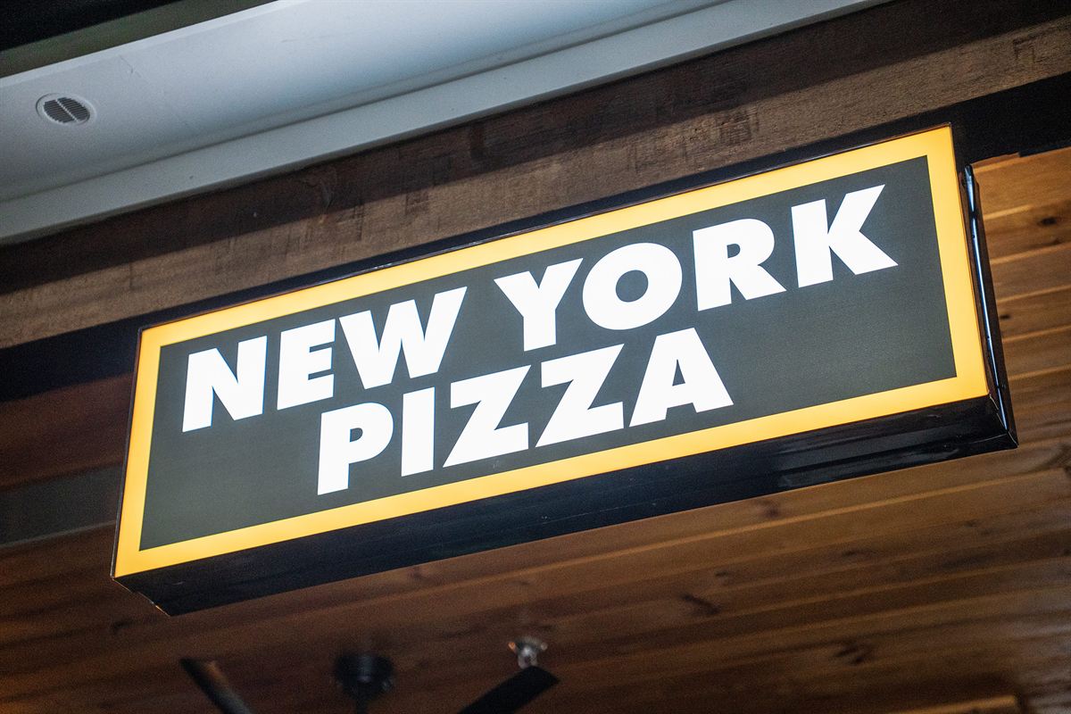 The lit New York Pizza sign inside the restaurant