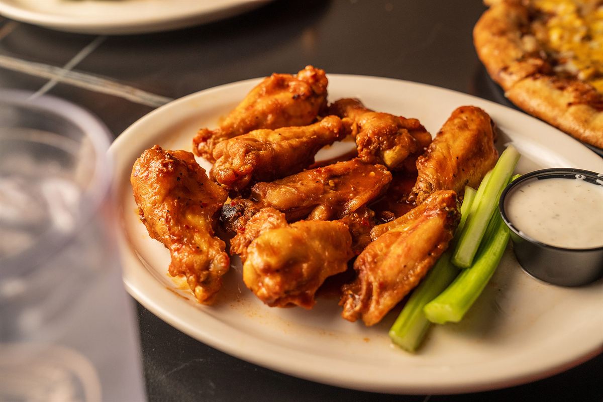 A plate of wings with celery and ranch